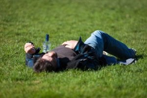 man lying on the ground with a bottle next to him