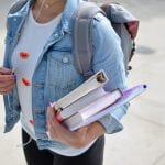 woman wearing backpack carrying books